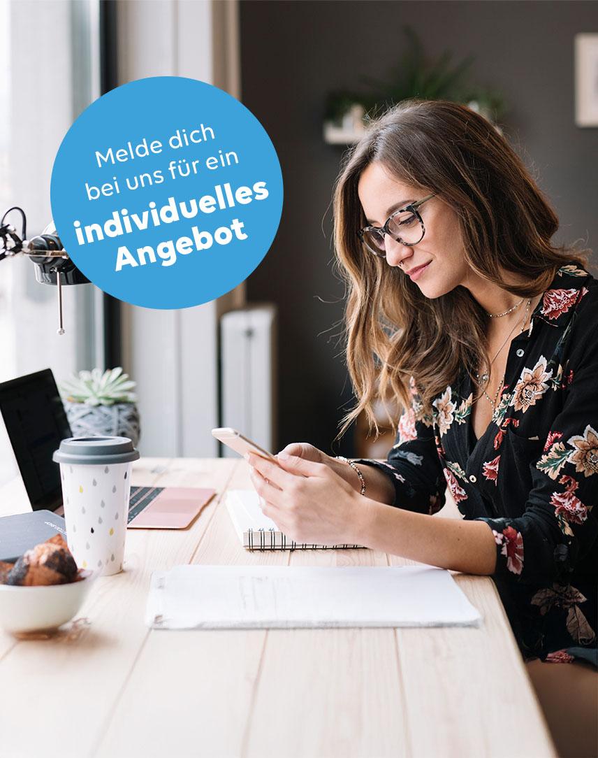 Frau am Schreibtisch mit Handy in der Hand