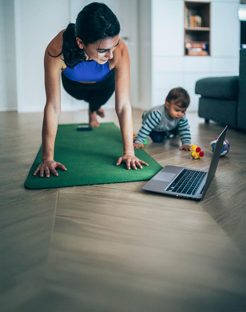 Mutter macht zuhause Sport, während ihr Baby neben ihr spielt